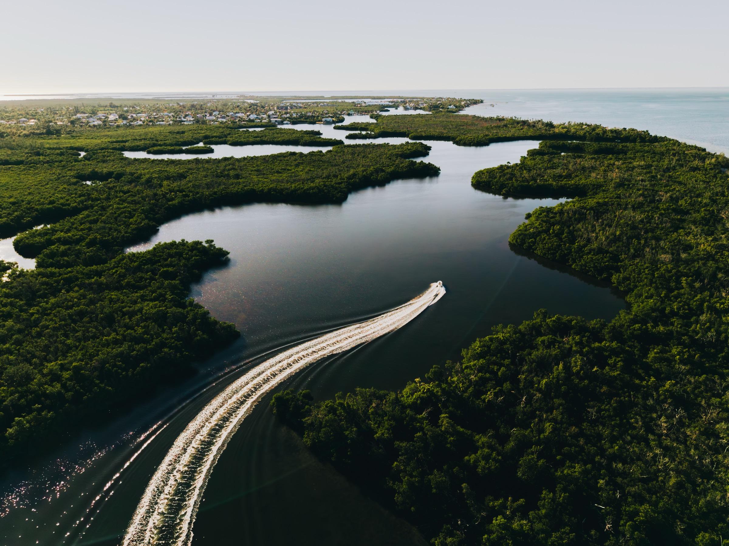 Aerial view of a fishing skiff cutting through mangrove channels near Pine Island