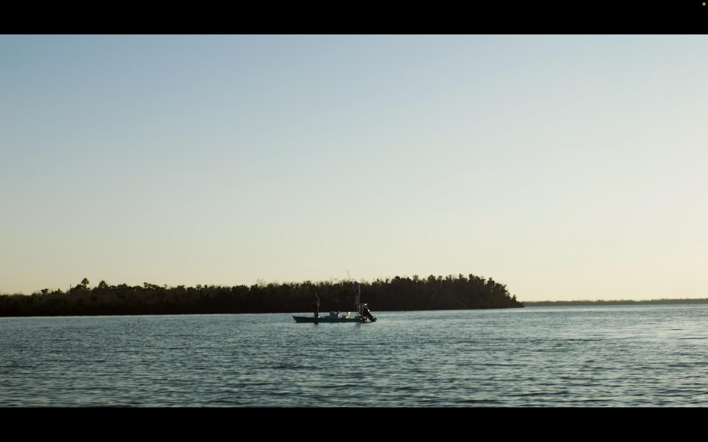 Skiff anchored near a mangrove point at golden hour