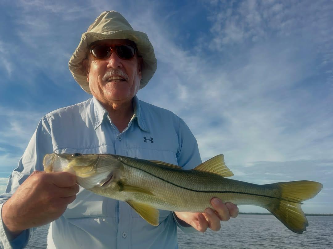 Angler holding a snook on Pine Island Sound under a blue sky